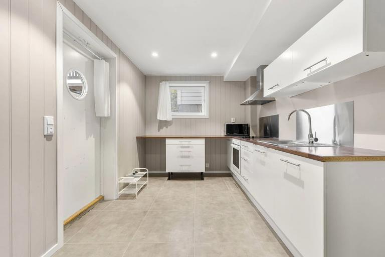 Kjøkkeninnredningen er klassisk og hvit med laminat benkeplate og frittstående hvitevarer.