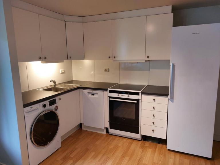 Kjøkken inkludert hvitevarer: kjøleskap, komfyr og vaskemaskin med tørk.