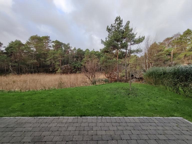 Hage rett på utsiden av praktikantdel mot natur. Dette er også utsikten fra stue/kjøkken og et av soverommene. 