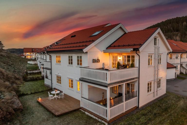 Leilighet på bakkeplan med overbygget terrasse, platting og plen.