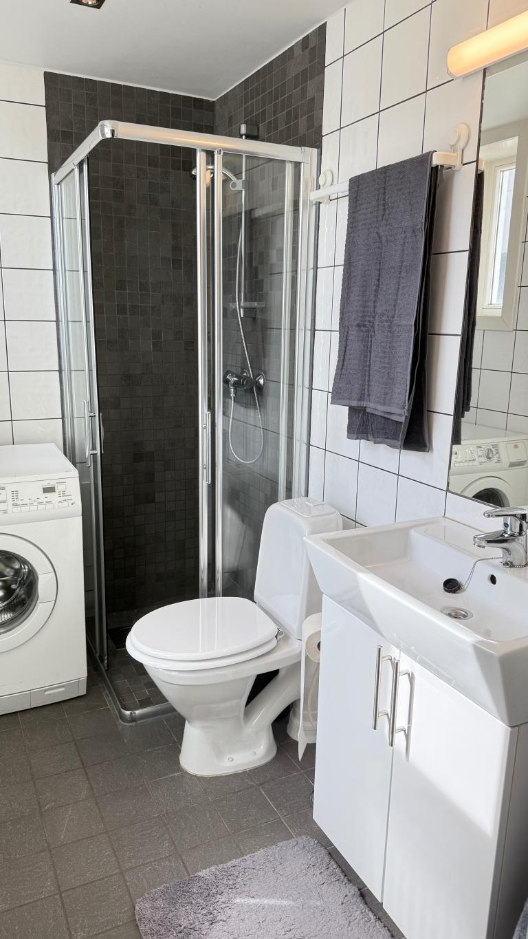 Moderne bad med dusjhjørne og vaskemaskin